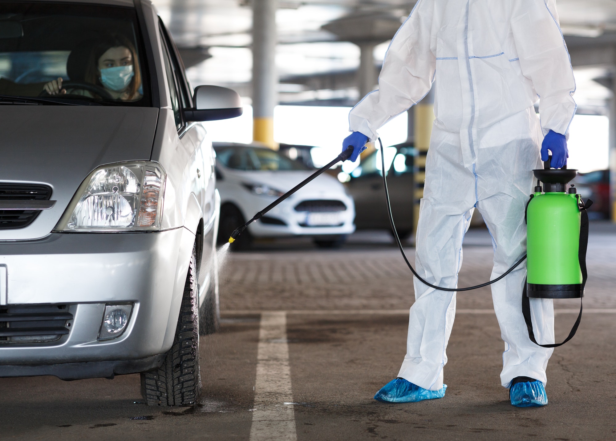 unrecognizable-person-disinfecting-car-with-spray-with-woman-inside.jpg